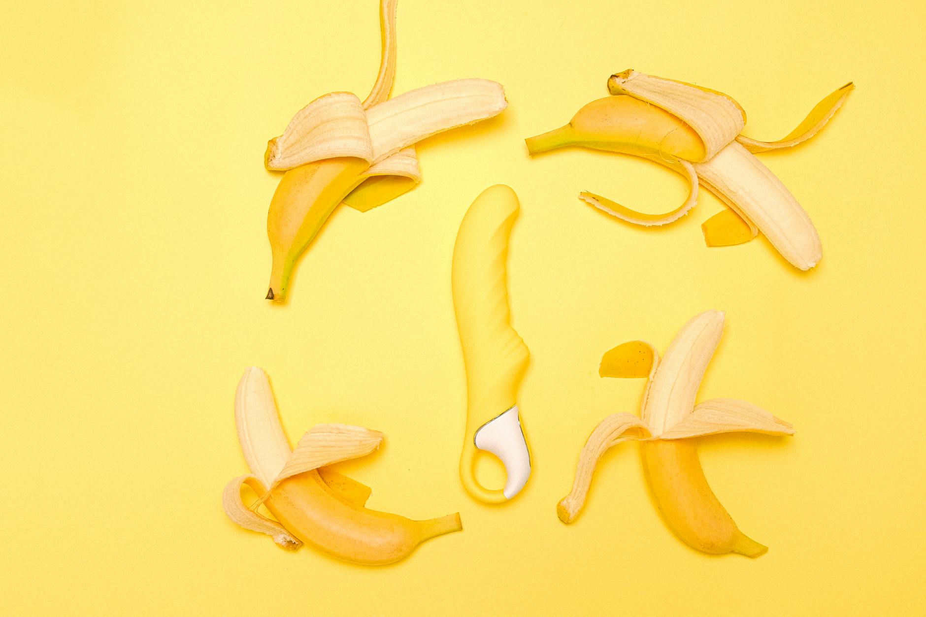 Yellow silicone lemon vibrator surrounded by fresh lemons on a bright background