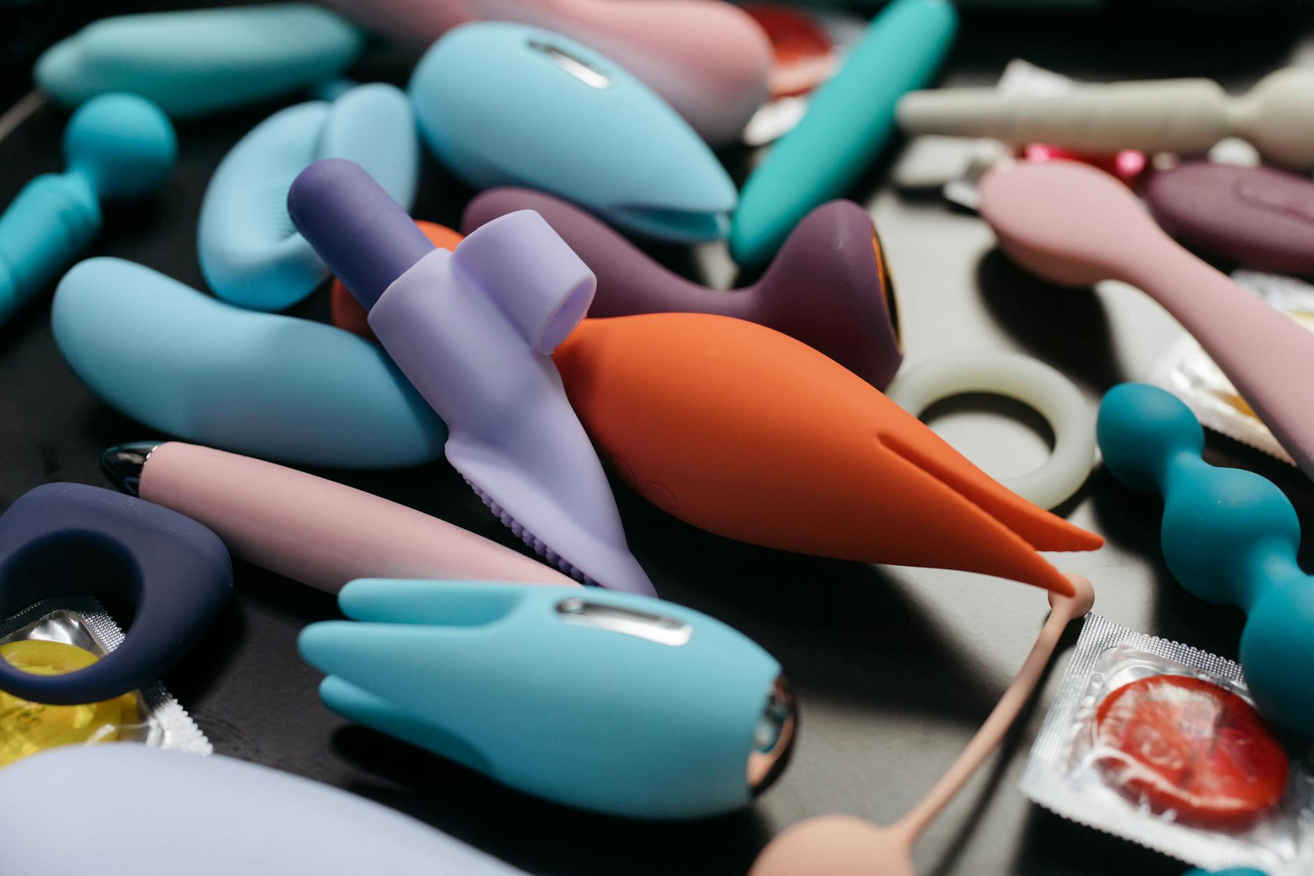 Two hands holding pink and blue silicone vibrators against a pastel background, representing reconnection and intimacy