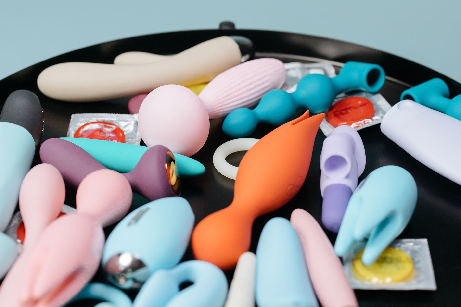 Colorful clitoral vibrators with flowers in a holographic gift bag on a yellow background