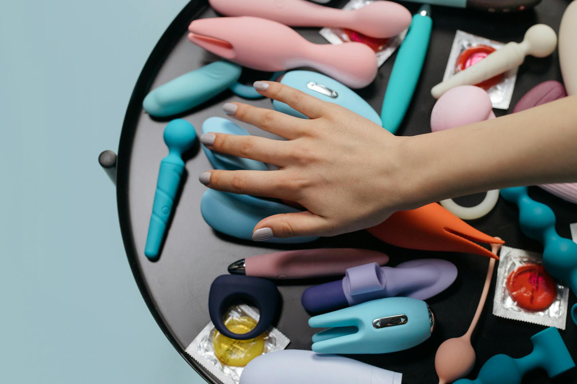 A hand holding a blue silicone toy against a purple background, promoting self-aware pleasure and control