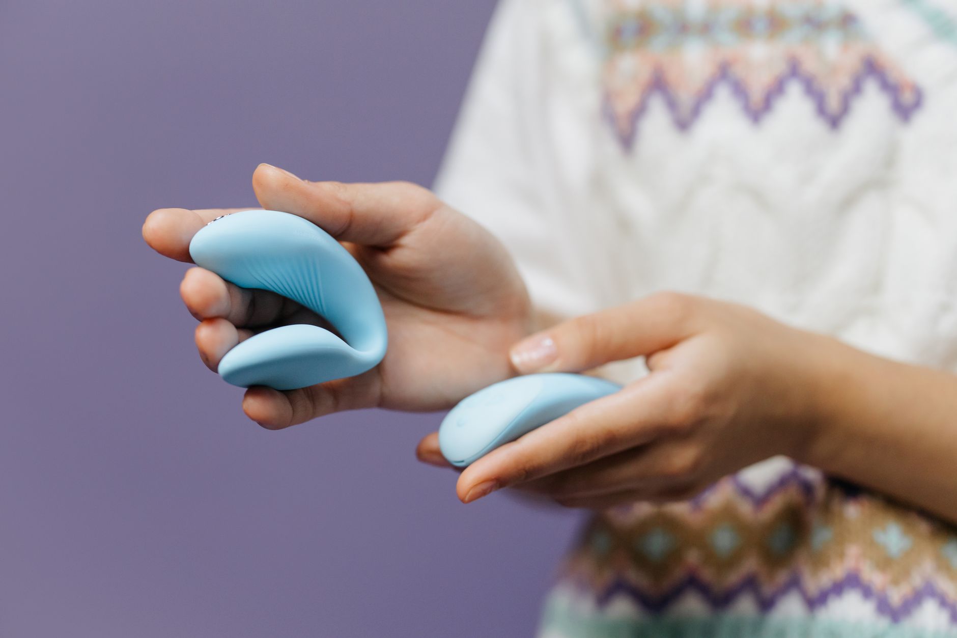 Close-up of hands holding a sleek blue vibrator, representing modern pleasure tools for hormonal shifts.