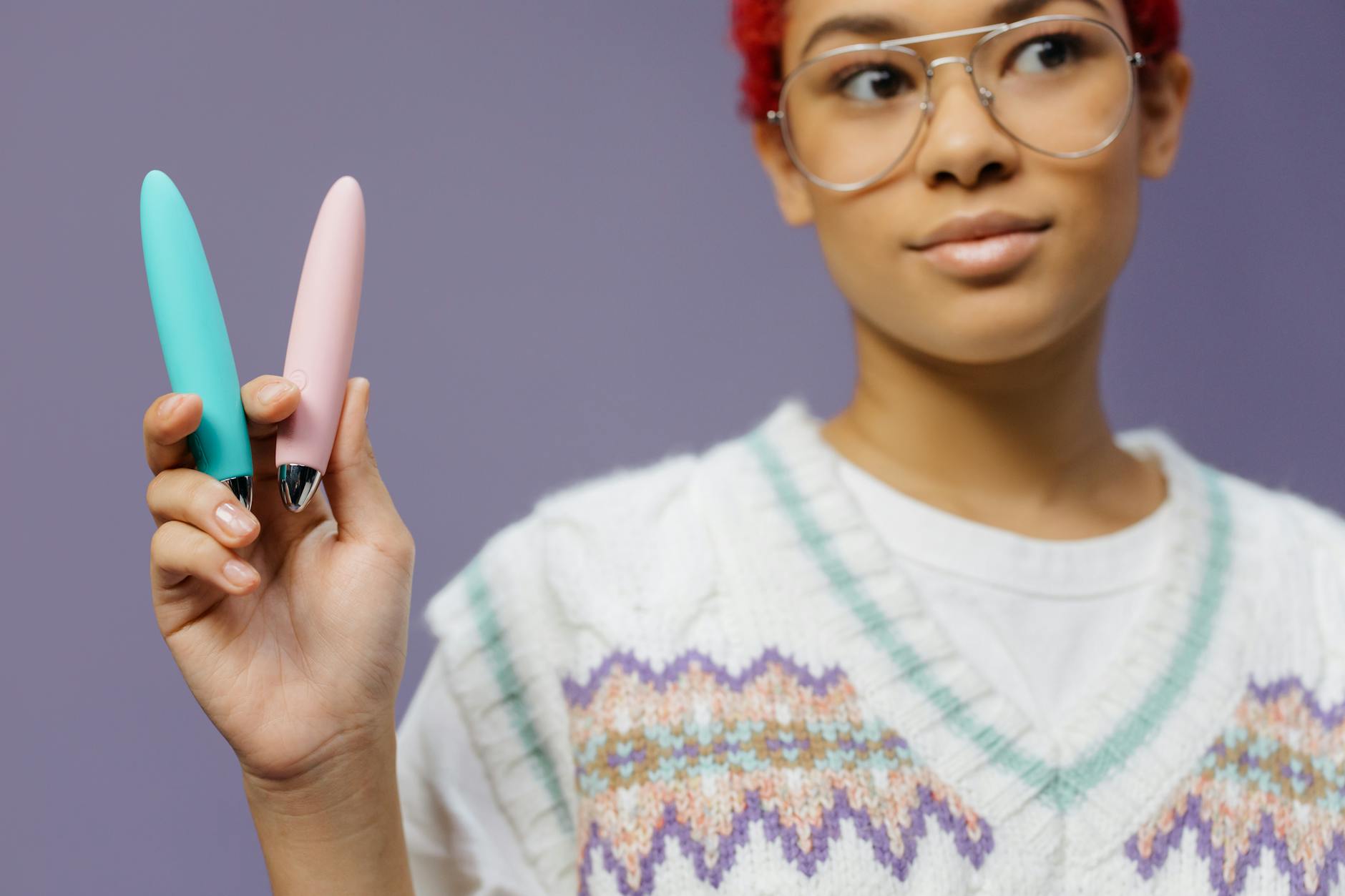 Person holding colorful lemon vibrators against purple background