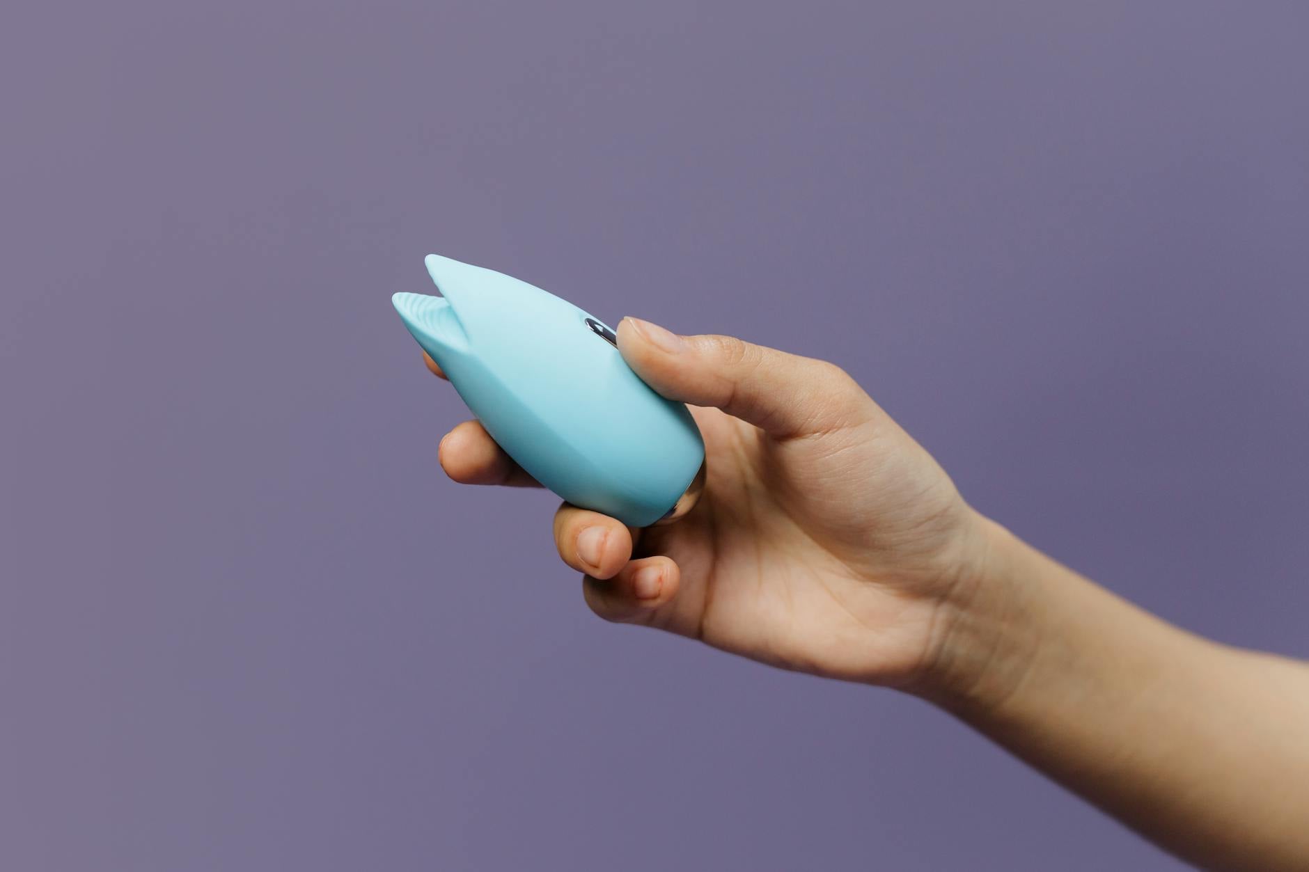A blue silicone vibrator held in hand, representing high-intensity pleasure and sexual satisfaction