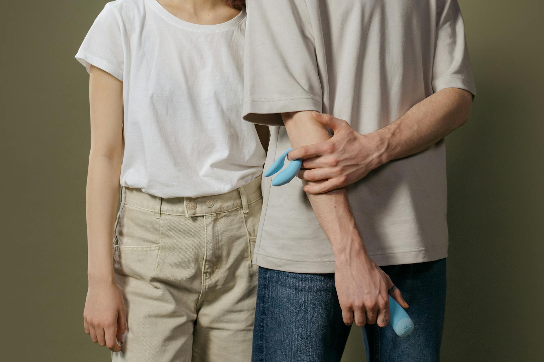 A couple holds a blue vibrator together, symbolizing reconnection and trust.