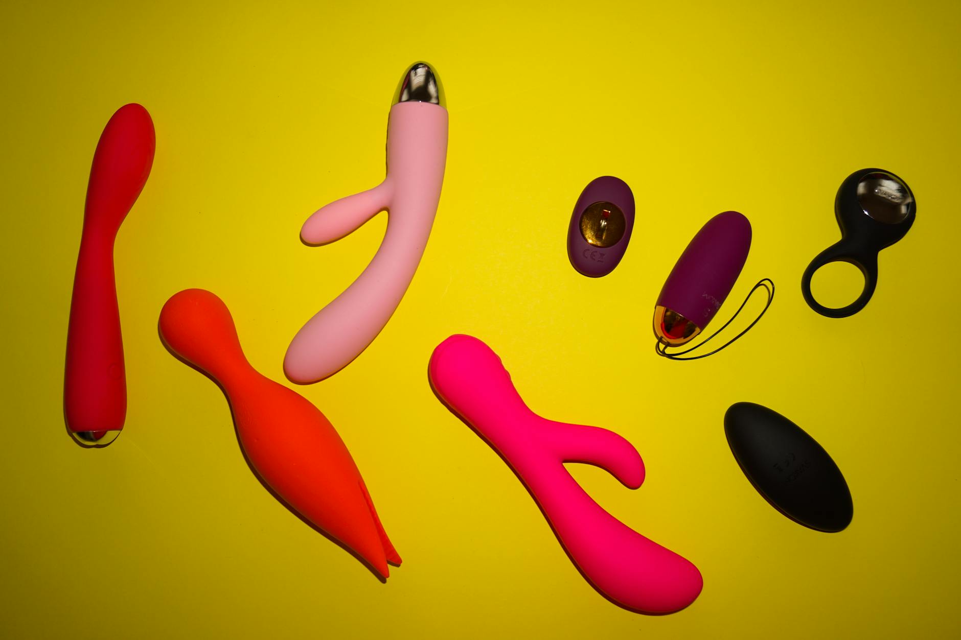 Vibrant assortment of colorful sex toys on bright yellow background