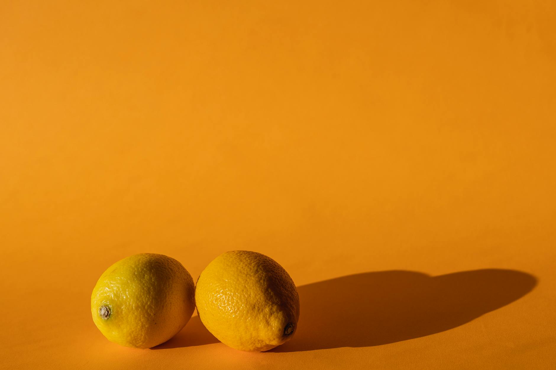 Fresh yellow lemons on a bright yellow background in studio lighting